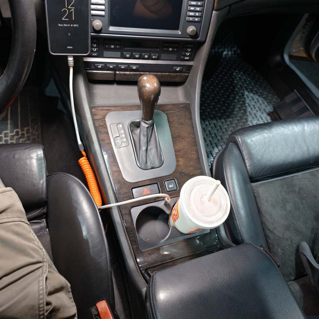 Wide installed view of the BMW E38 front cup holder with a drink and connected USB-C cable