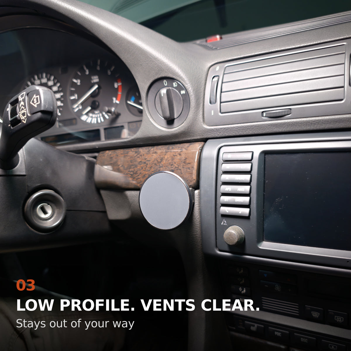 Low-profile BMW E38 phone mount beside the center display with the main air vents clear.