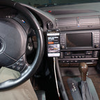 Wide BMW E38 interior view with the phone mounted beside the center display and a cable connected directly to the phone.