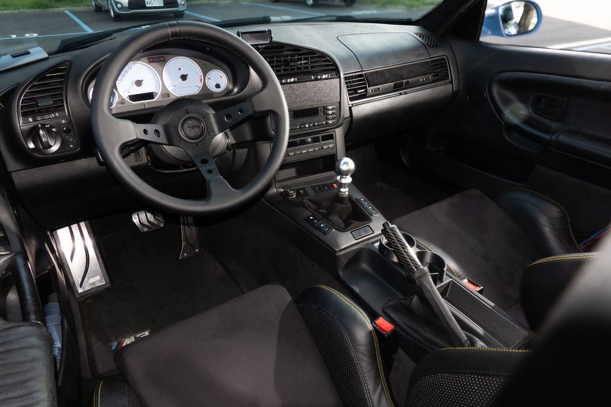 BMW E36 cockpit with cup holder and phone mount in everyday use.